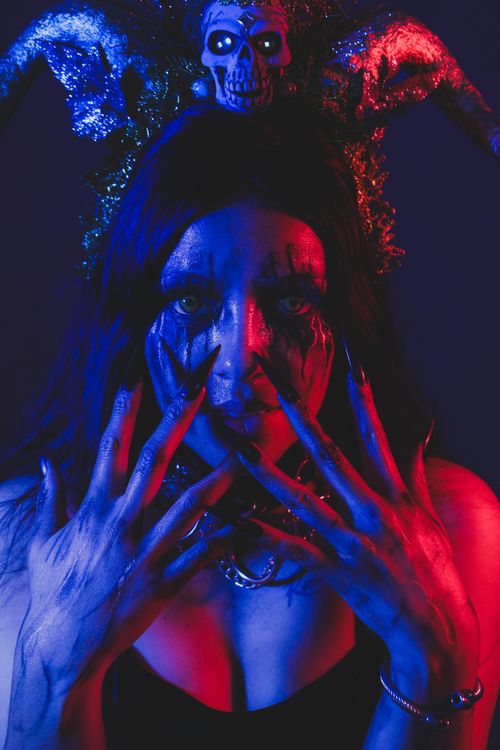 Free A moody portrait featuring Halloween-themed makeup and a skull headpiece, creatively lit. Stock Photo