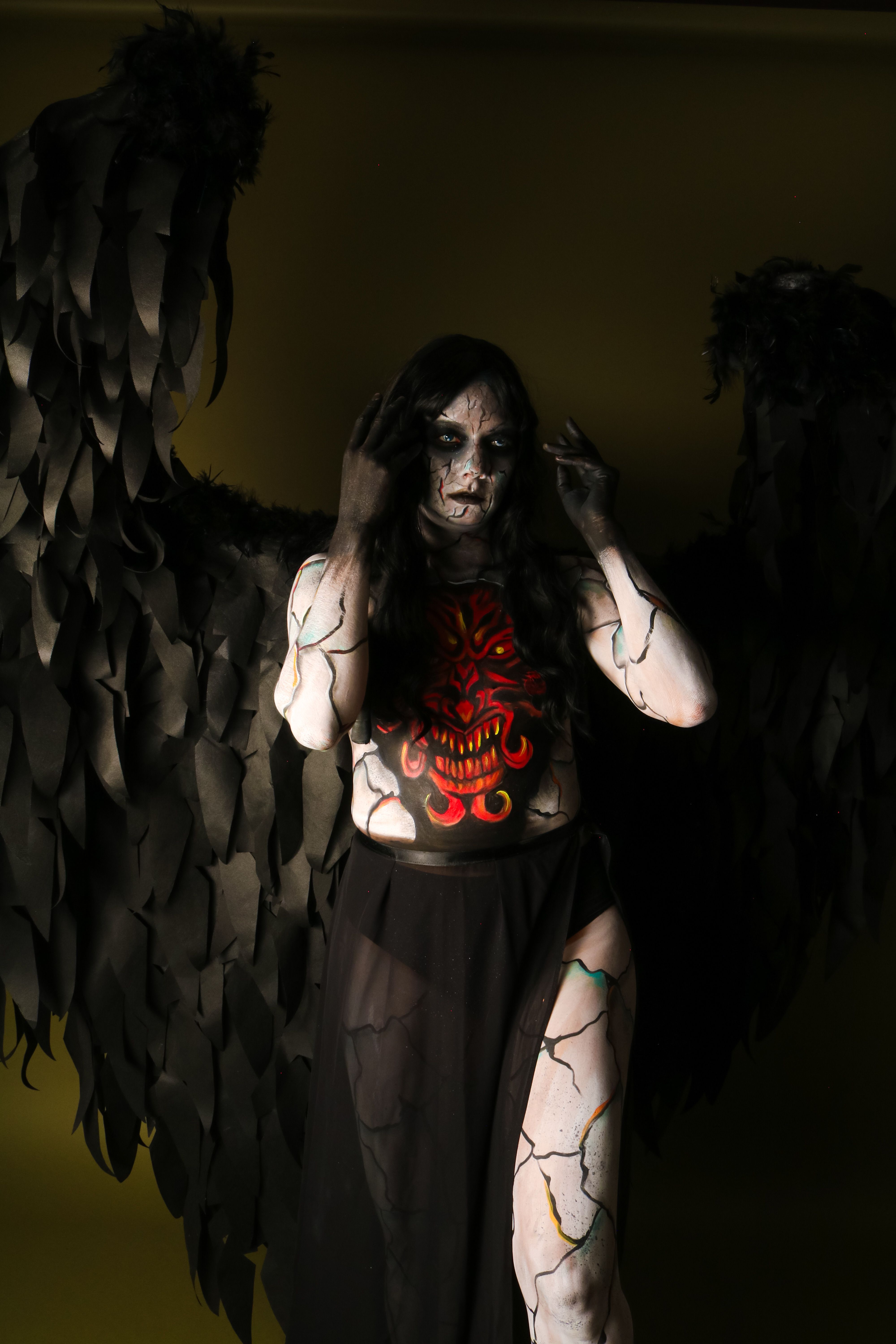 A person dressed as a dark angel with black wings and dramatic makeup.