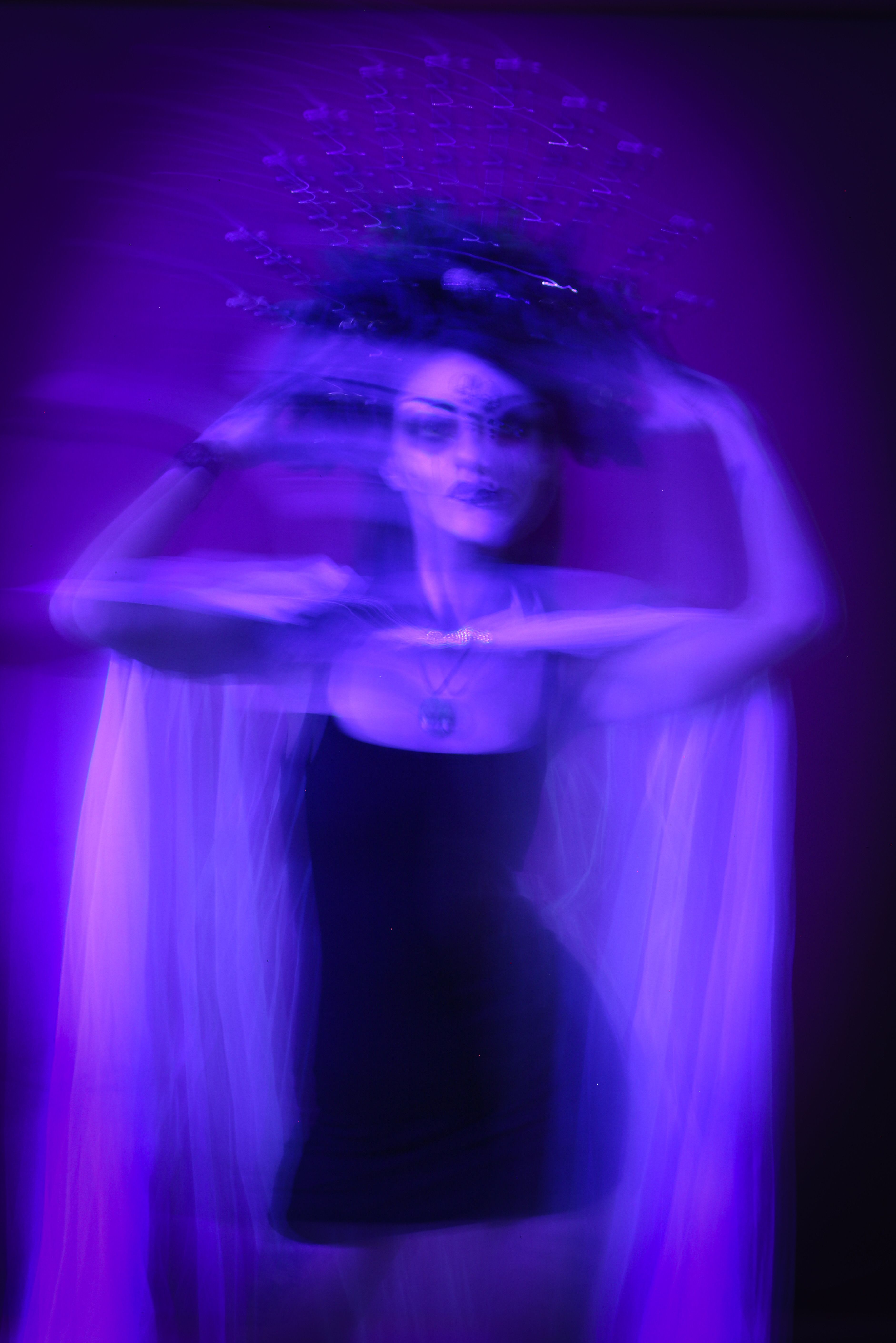Artistic motion blur of a woman in dim purple lighting creates a ghostly, ethereal effect.