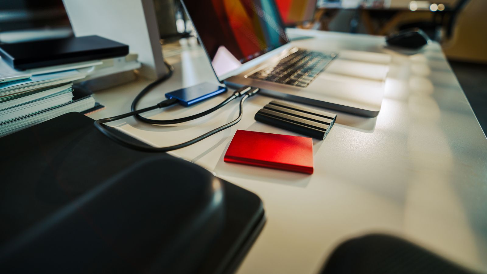 A tidy office desk with a laptop and external drives