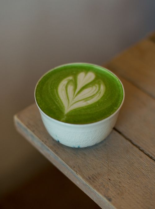 Free A close-up of a matcha latte with heart-shaped latte art in a cozy indoor setting. Stock Photo