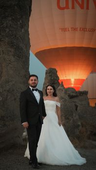 Elegant couple at sunrise with hot air balloons in the background.