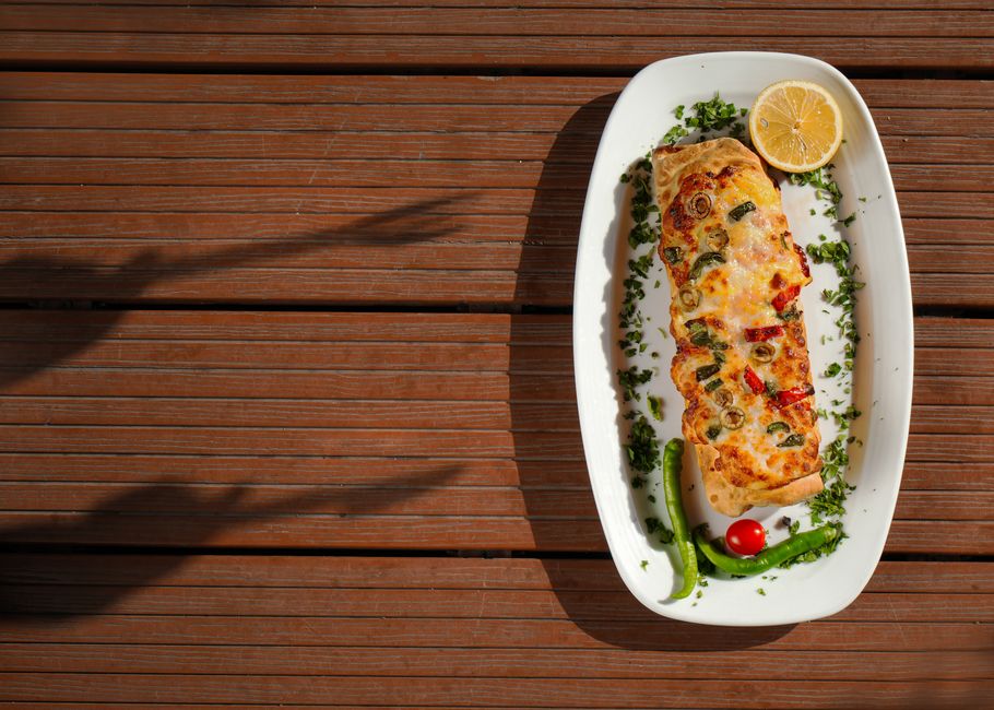 Photo by Shahin Mren on Pexels Delicious Turkish pide with fresh vegetables and lemon served on a wooden table. - Photo by Shahin Mren on Pexels