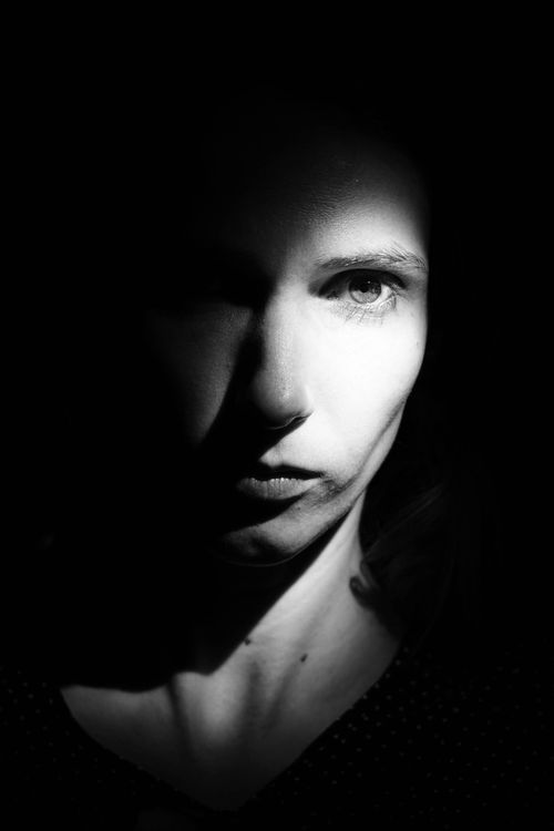 Free Moody black and white portrait capturing dramatic shadows on a woman's face. Stock Photo
