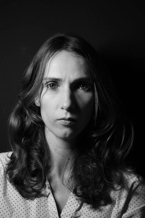 Free Black and white portrait of a woman with wavy hair, intense gaze, and textured background. Stock Photo