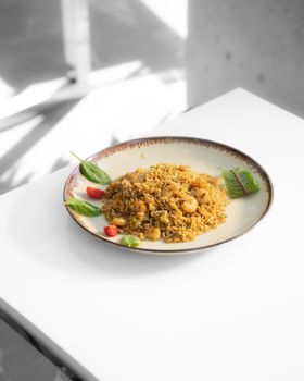 A plate of flavorful fried rice with shrimp and garnishes on a clean white table.