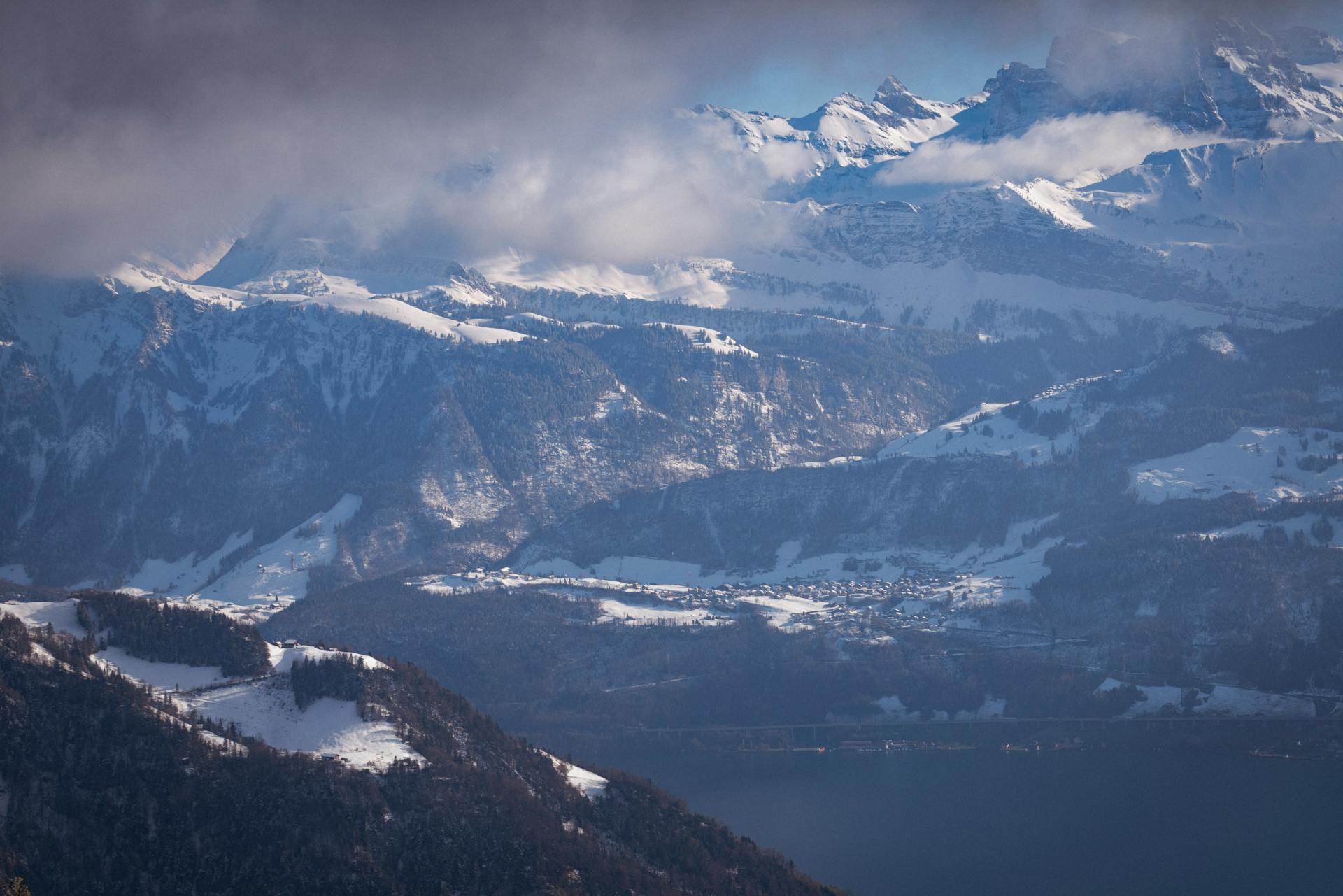 Stunning winter landscape of the Swiss Alps with snowcapped peaks and a serene valley below.