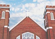 红砖教堂的十字架和拱形窗户映衬在蓝天下