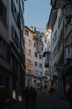 A picturesque narrow street in Zürich's Old Town with people strolling and historic architecture.
