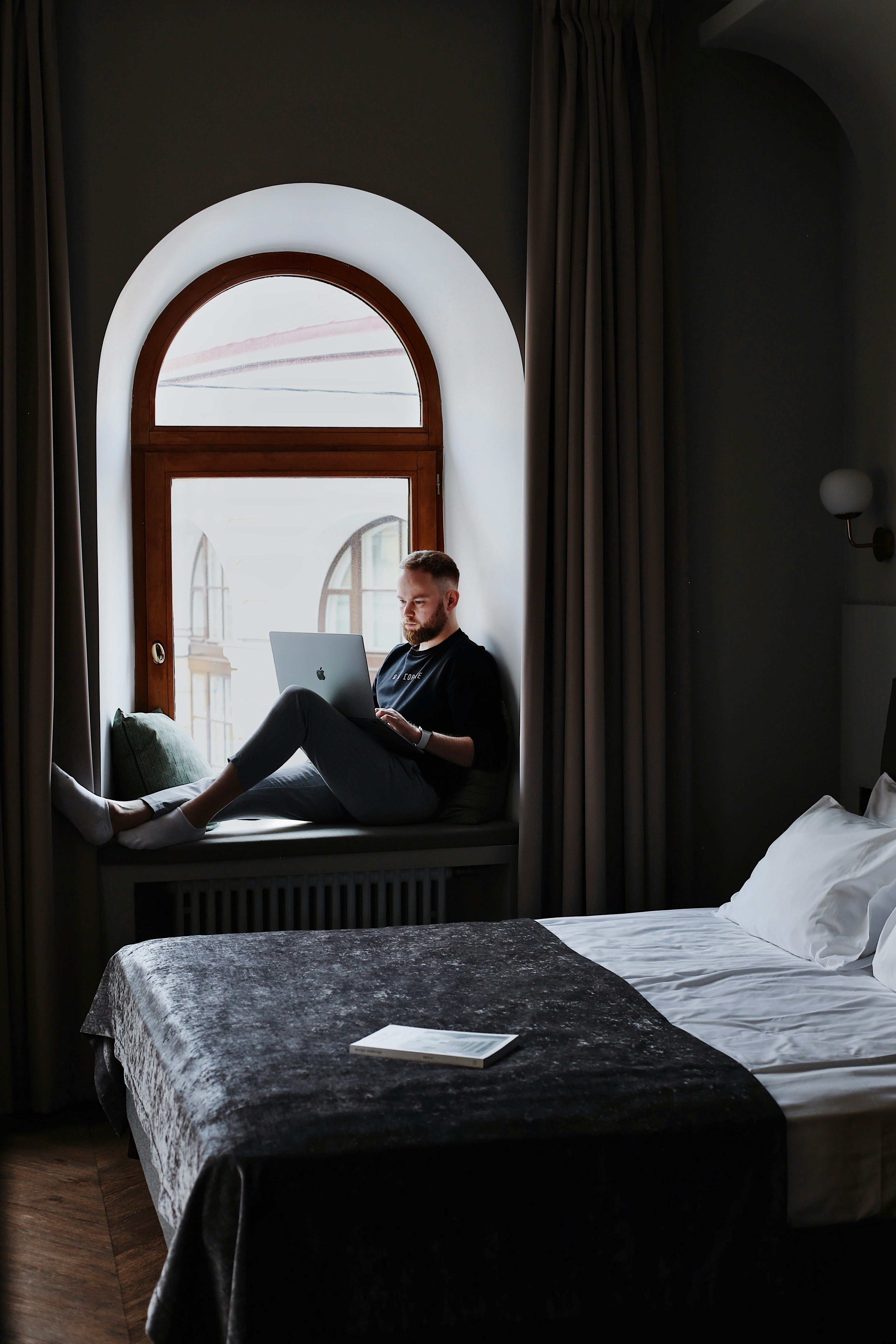 Traveler with a laptop in a hotel room booking a stay