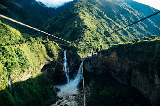在明亮的天空下，瀑布从郁郁葱葱的青山中倾泻而下，展现了大自然的宁静之美