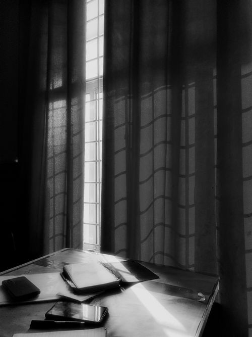 Free Artistic black and white image capturing sunlight streaming through curtains onto a desk in Dehradun. Stock Photo