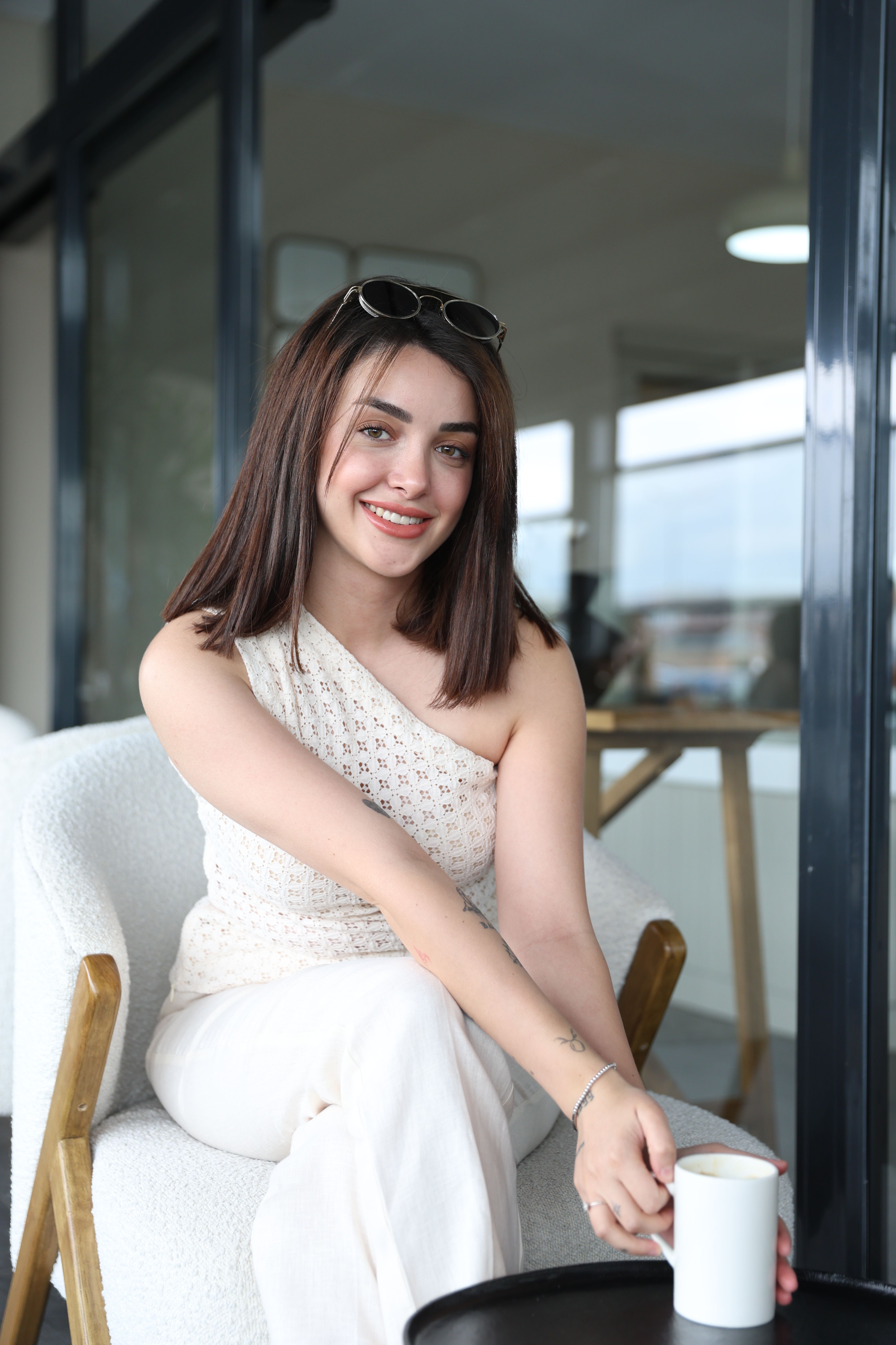 A young woman enjoys coffee indoors, exuding warmth and relaxation.