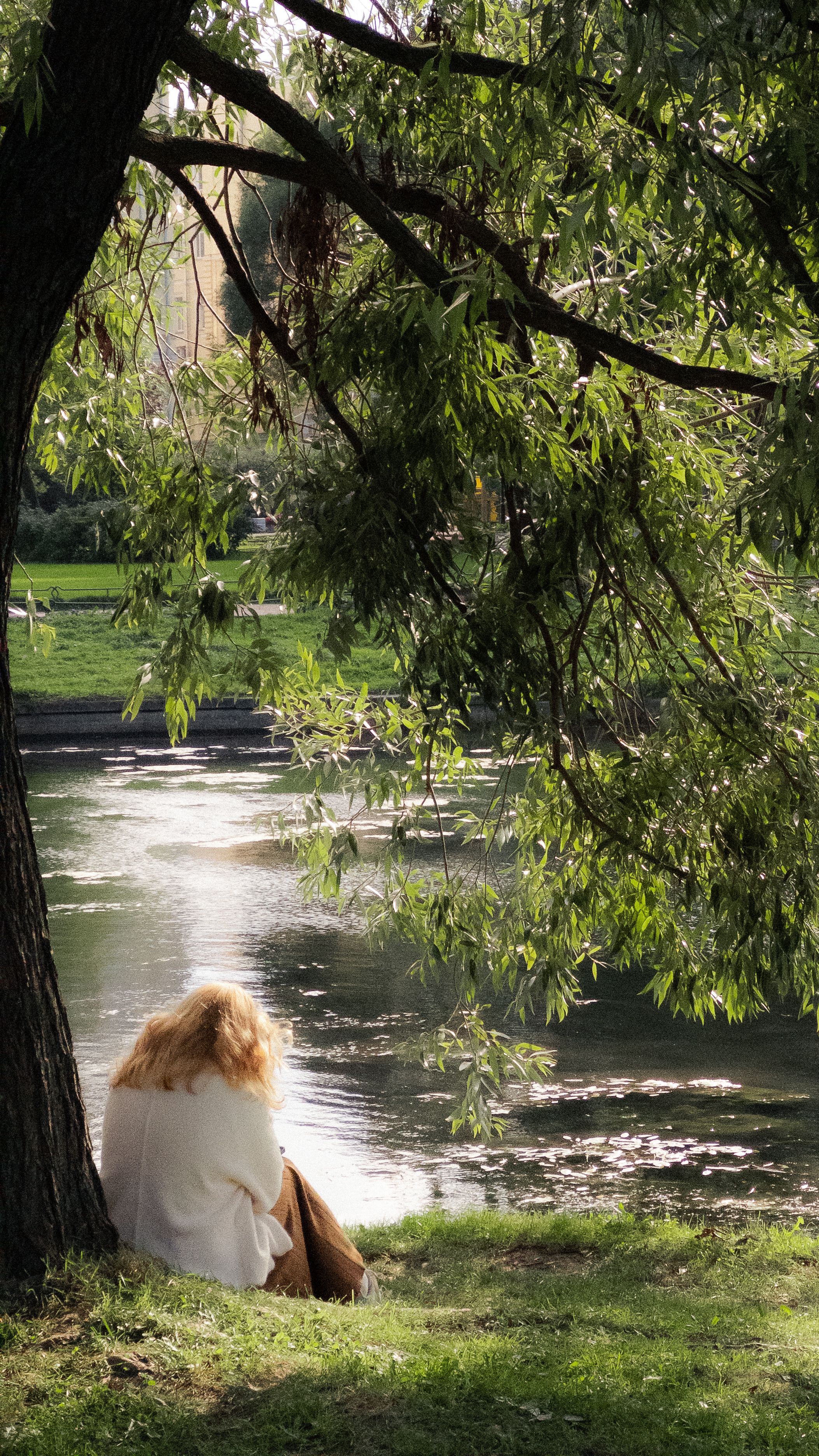Woman Relaxing by Tranquil Riverside in Park · Free Stock Photo