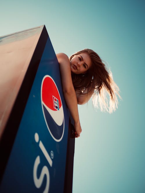 Foto Di Angolo Basso Della Donna In Cima Alla Posa Del Frigorifero Di Pepsi