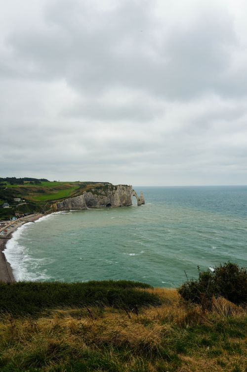 Free A picturesque view of the famous Étretat cliffs against a cloudy sky, overlooking the sea. Stock Photo
