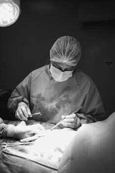 A surgeon in an operating room performing surgery under bright lights, wearing surgical attire.