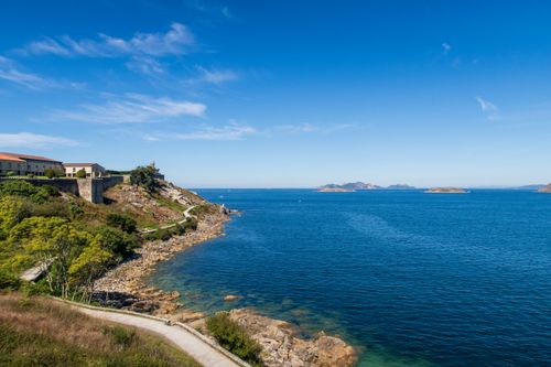 Free Beautiful coastal landscape of Galicia with clear blue sea, cliffs, and distant islands. Stock Photo