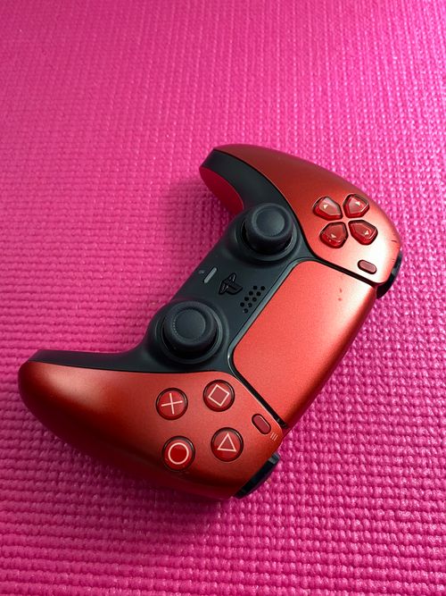Free A vibrant red gaming controller placed on a textured pink background. Stock Photo