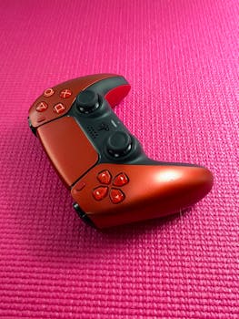 Red game controller on a textured pink background.