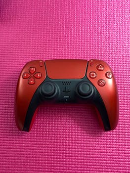 Red gaming controller on pink mat, contrasting vivid colors for dynamic gaming setup.