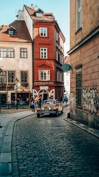 Cobblestone street with vintage car and colorful buildings in a European city.