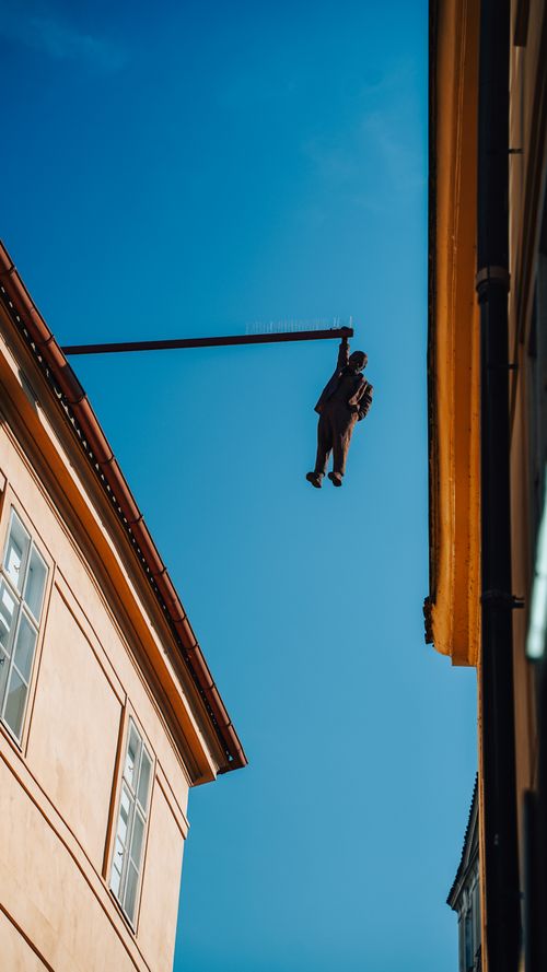 Free Artistic sculpture suspended between buildings in an urban setting against a clear sky. Stock Photo
