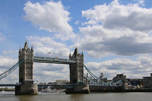 A stunning view of the Tower Bridge in London with fluffy clouds and a bright blue sky.
