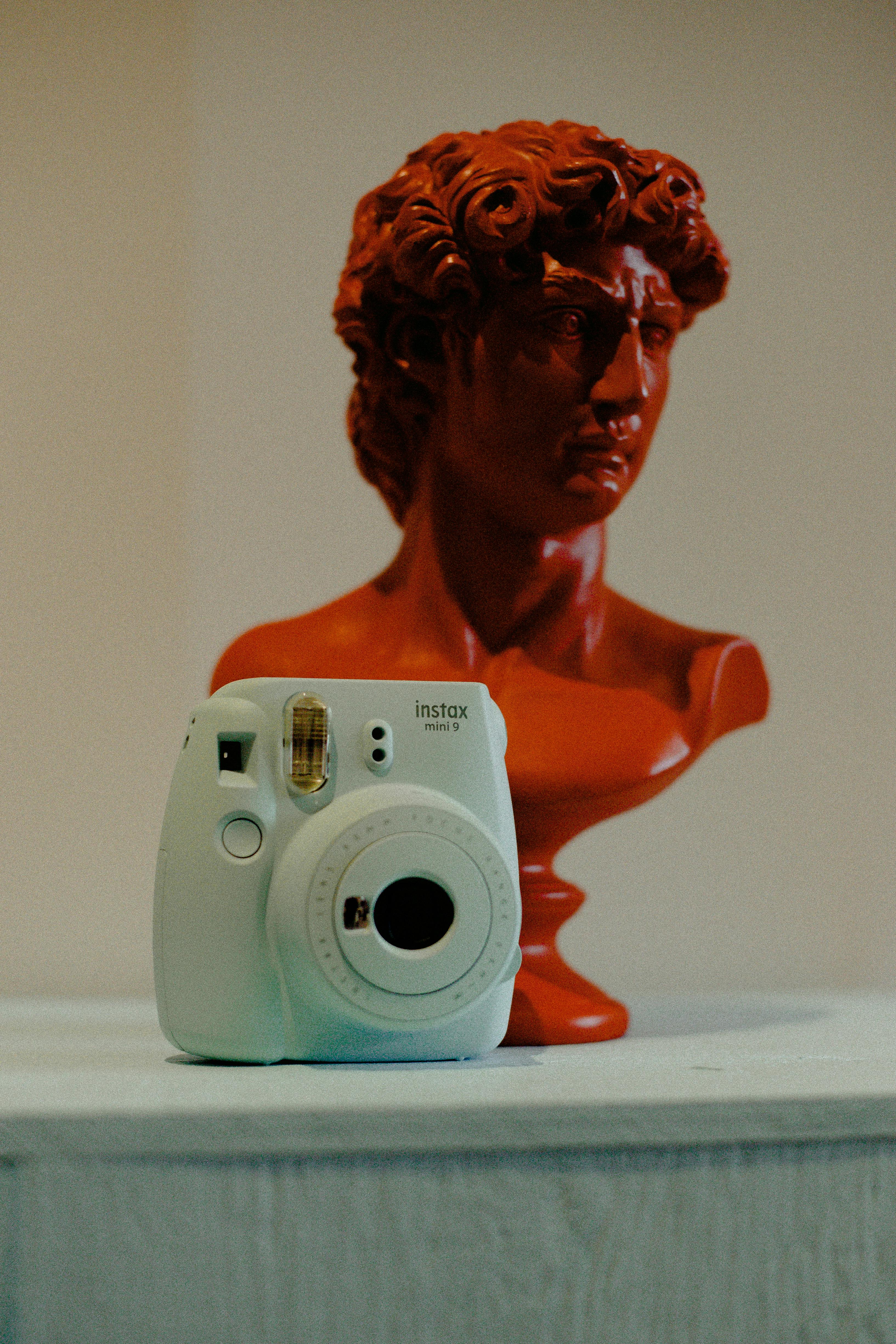 blue fujifilm instax mini camera near man head bust