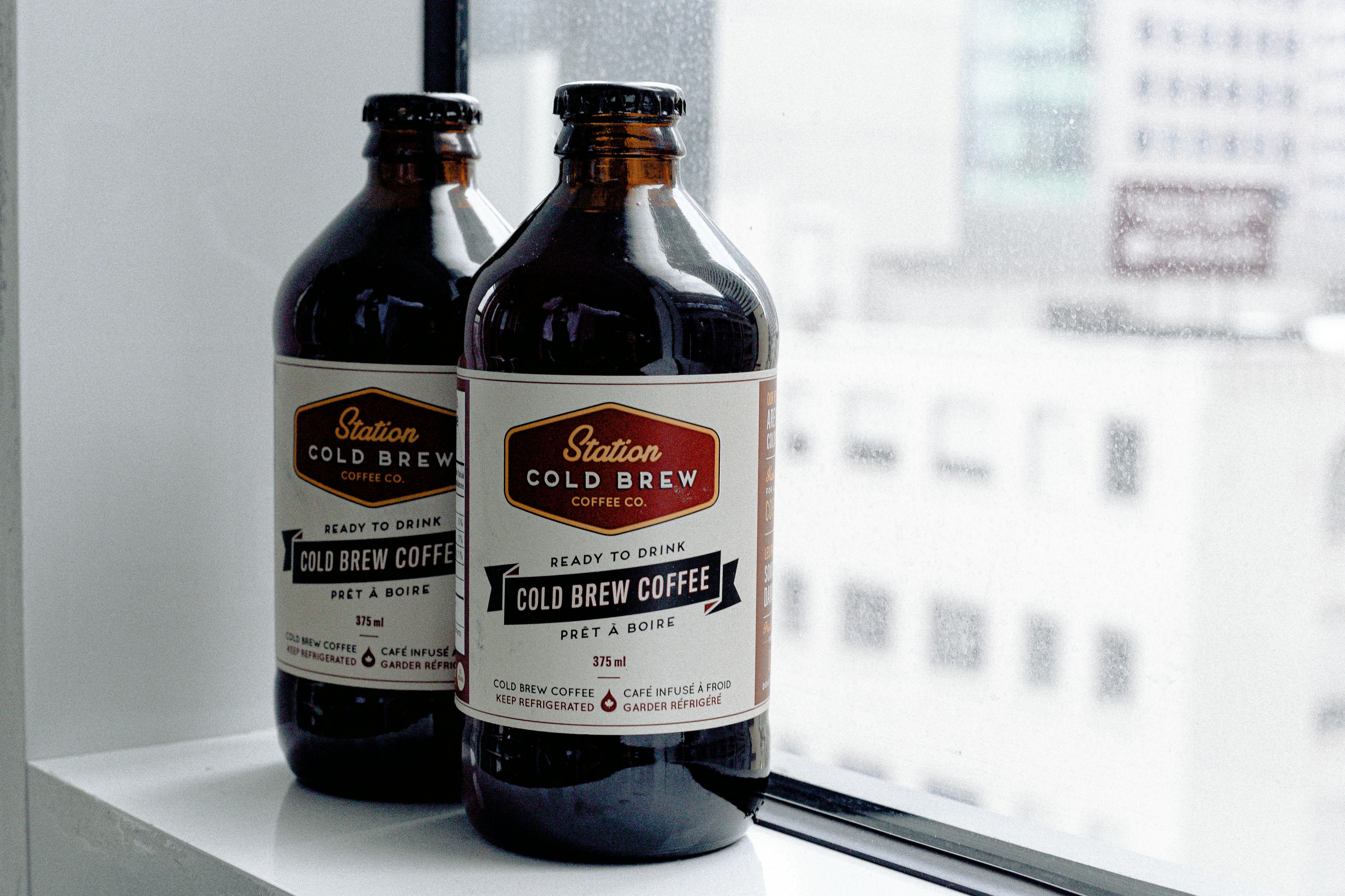 Two glass bottles of cold brew coffee placed on a window ledge, ready to drink.
