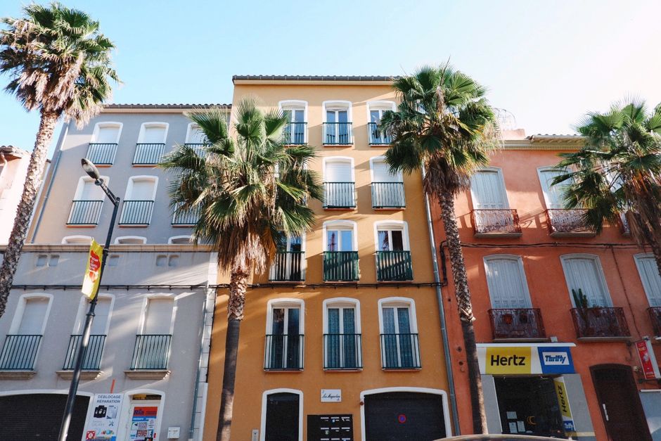 Vibrantes edificios de apartamentos con palmeras a lo largo de una calle soleada, perfectos para temas de viaje y urbanos.
