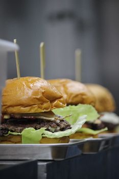 Close-up of fresh gourmet burgers with lettuce and cheese ready to serve.