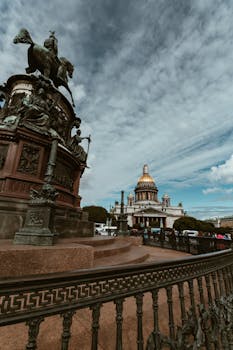 蓝天下的圣以撒大教堂和雕像，在云层映衬下，构成令人惊叹的户外景观