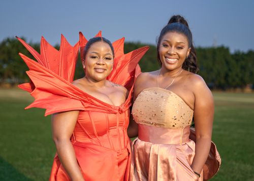 Free Two women in colorful evening gowns smiling outdoors. Captured in daylight, showcasing fashion and friendship. Stock Photo