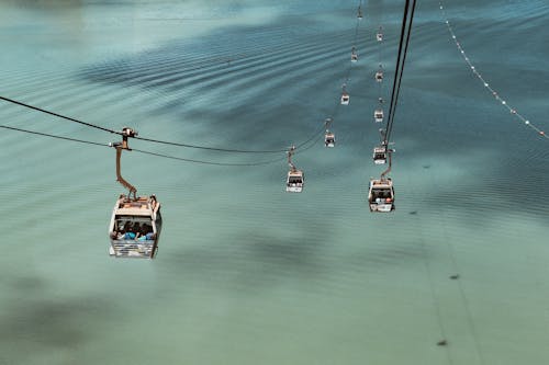 People Riding Cable Cars Viewing Body of Water