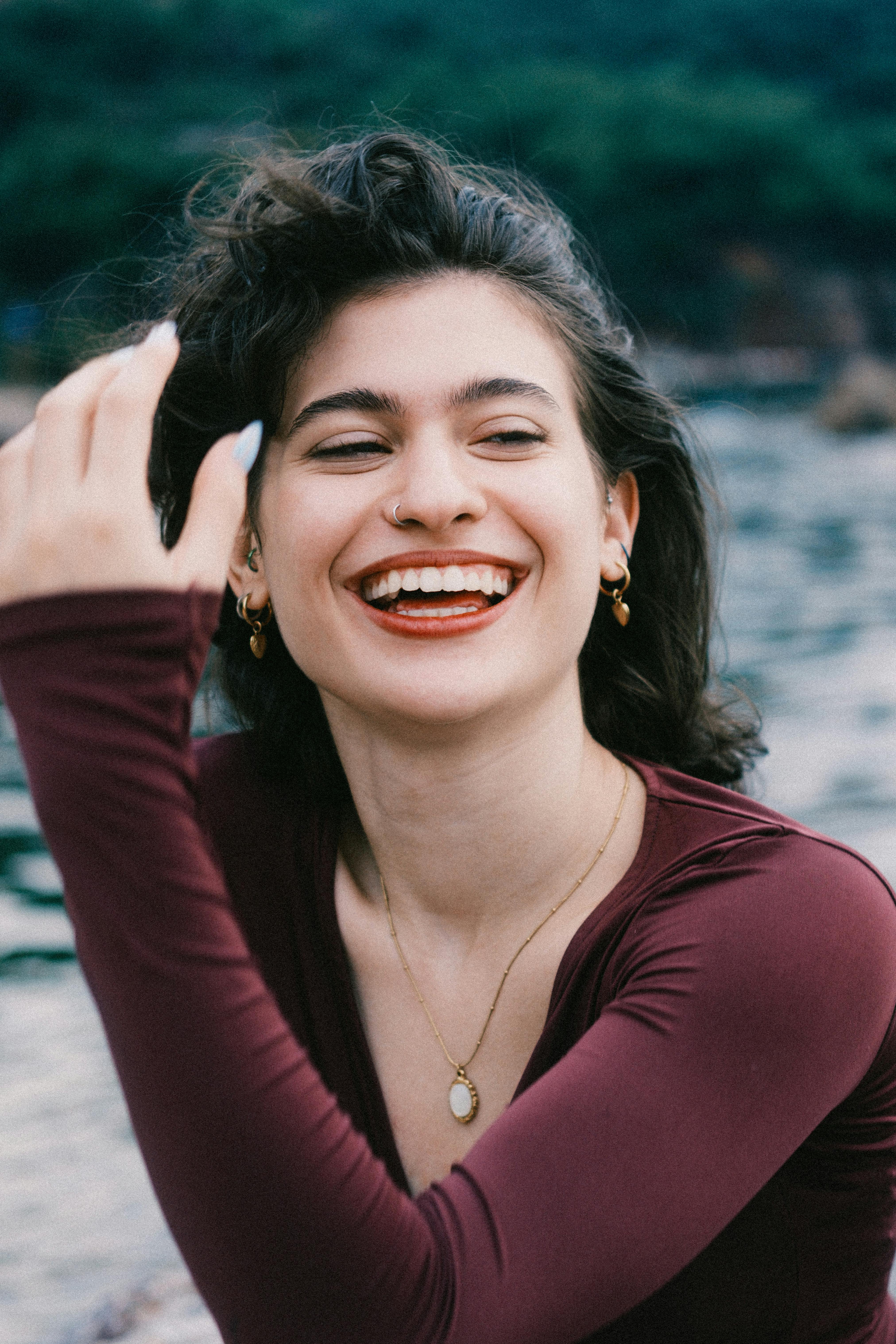 Cheerful woman laughing in an outdoor setting by the water. Capturing joy and spontaneity.