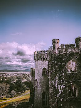 Ancient castle ruins overlook a picturesque landscape under a dramatic sky.