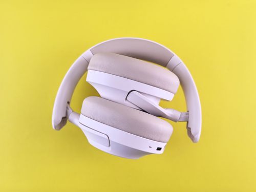 Free Stylish over-ear headphones in white against a vivid yellow backdrop. Ideal for tech lifestyle imagery. Stock Photo