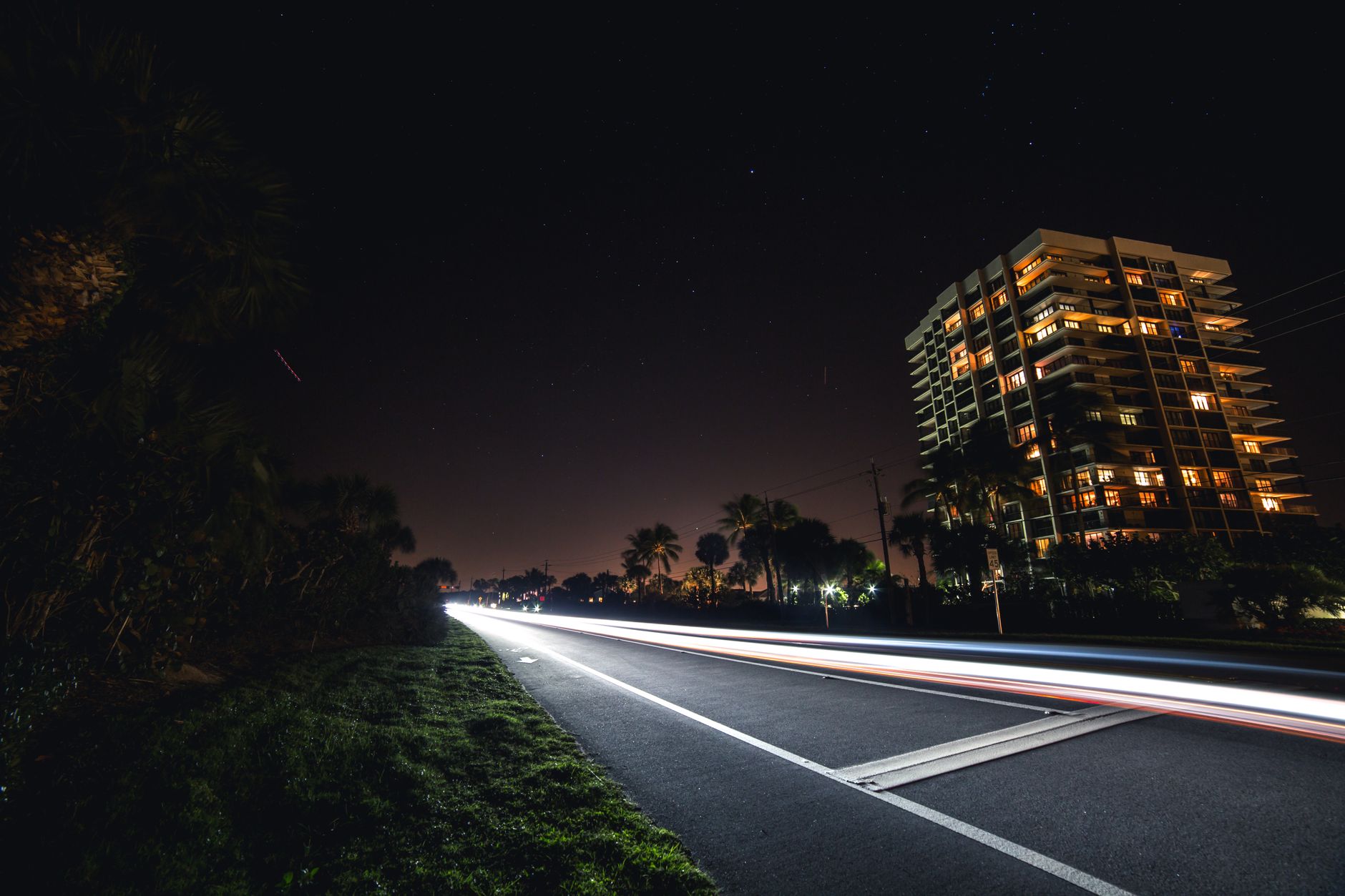 Night view of a city road with moving lights and a prominently lit building.