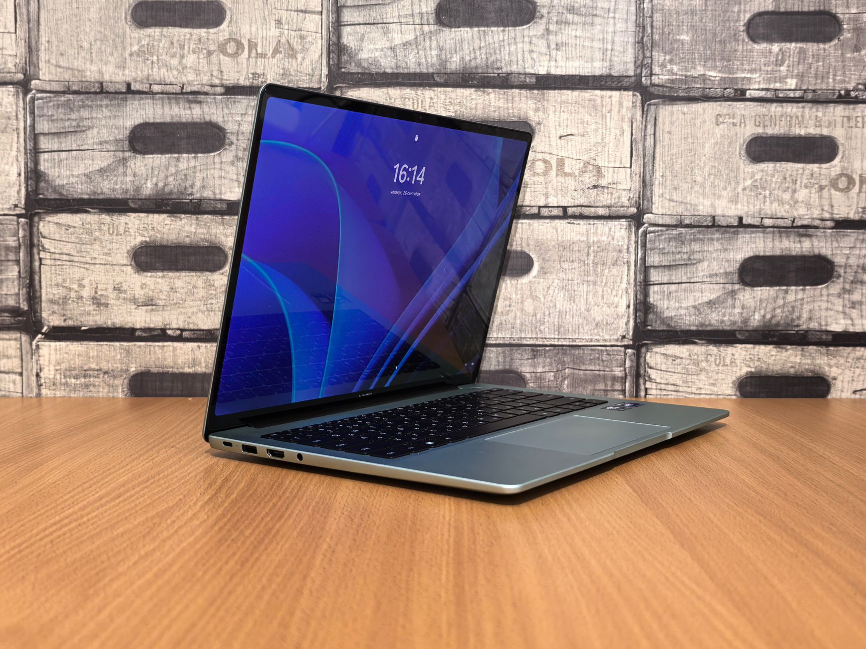 Side view of an open laptop on a wooden desk with crate-style background.