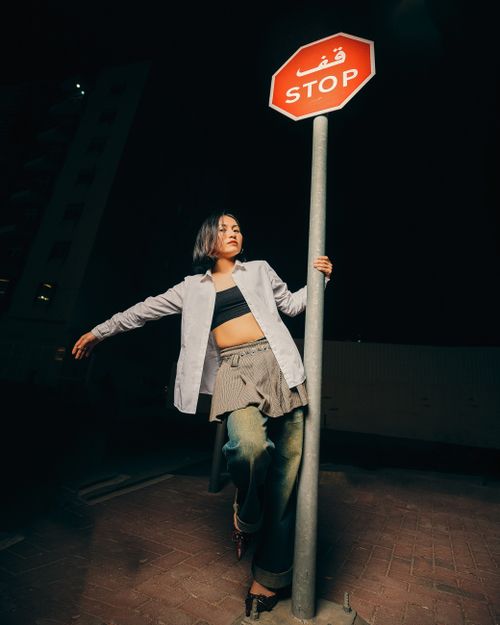 Free Stylish woman poses with stop sign at night, urban setting. Stock Photo