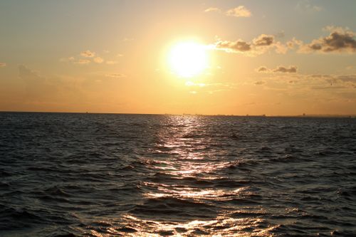 Free Stunning ocean view during sunset with golden hues and reflective water. Stock Photo