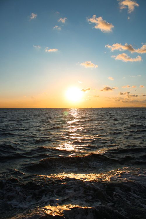 Free Vivid ocean sunset with golden reflections on water and cloudy sky. Stock Photo