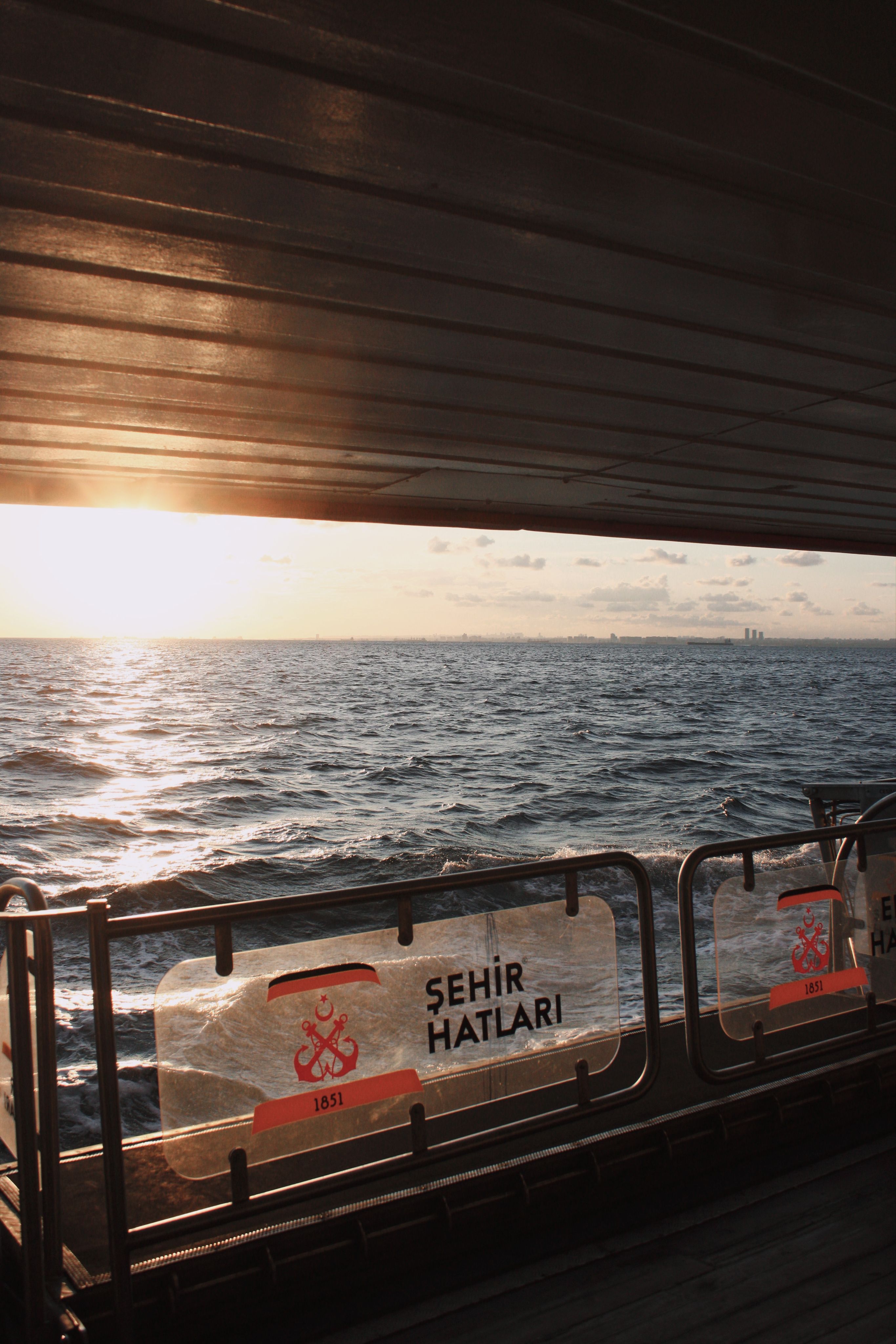 Sunset view of the Bosphorus from a ferry, capturing the serene sea and distant skyline.