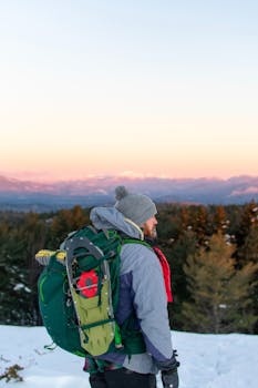 在新罕布什尔州林肯市，一名独自背着背包的徒步旅行者正在白雪覆盖的山上享受冬日日出