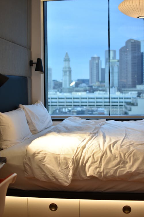 Белые подушки на кровати у окна