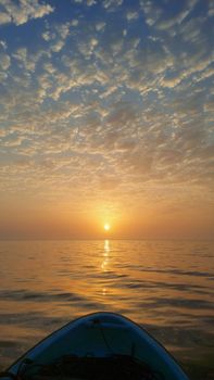Captivating sunrise over calm ocean with a kayak foreground, vibrant sky reflection.