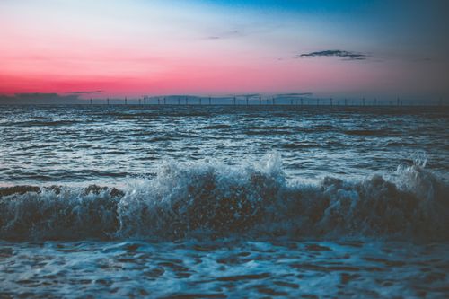 Free Captivating scene of ocean waves crashing under a breathtaking sunset sky. Stock Photo
