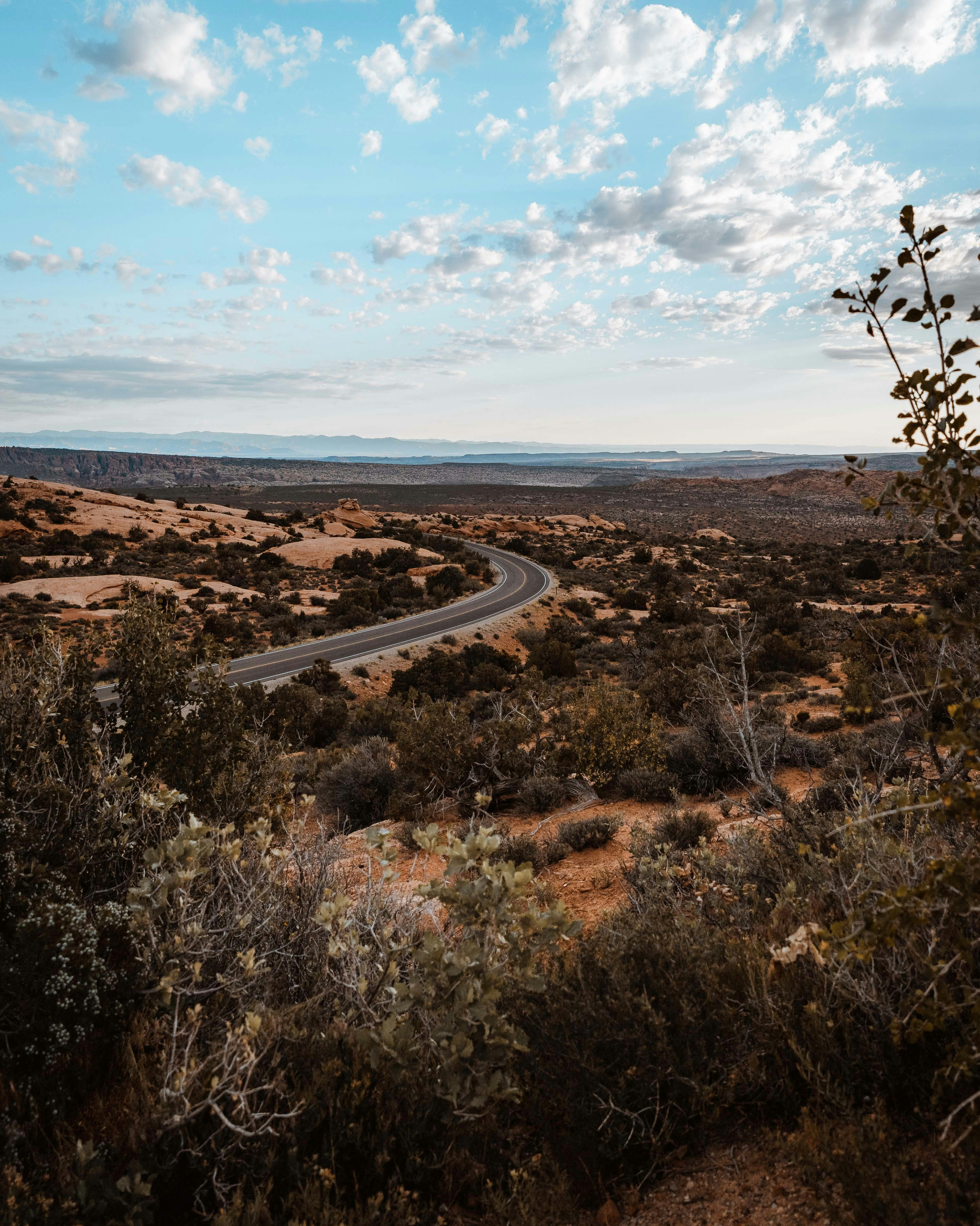蜿蜒的高速公路穿过沙漠，头顶是蔚蓝的天空和零散的云层
