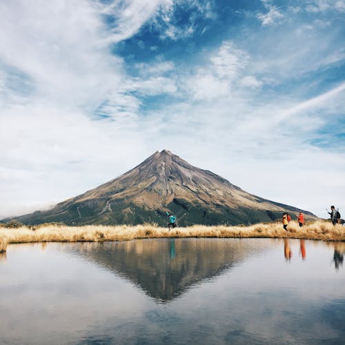 Brown and Black Mountain in Front of Body of Water